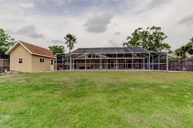 back of property with stucco siding, fence, a lawn, and a lanai