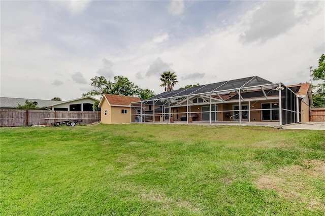 back of house with stucco siding, glass enclosure, fence, and a lawn