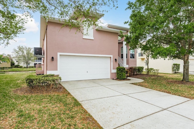 view of front facade featuring a front yard, an attached garage, driveway, and stucco siding