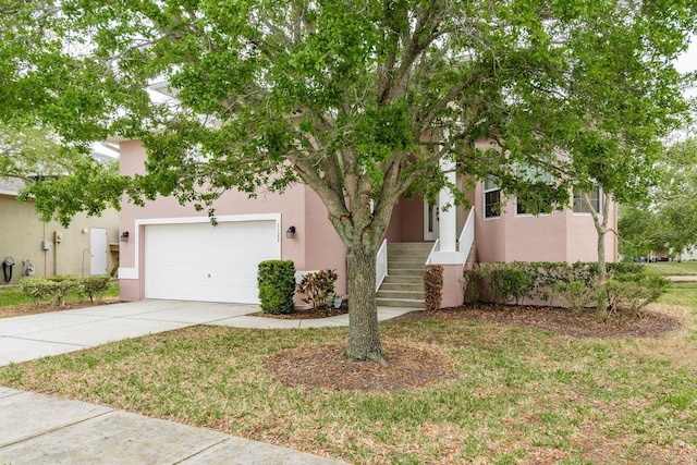 view of property hidden behind natural elements with driveway, stucco siding, and a garage