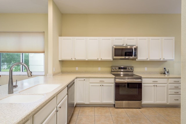 kitchen with stainless steel appliances, white cabinets, a sink, and light tile patterned flooring