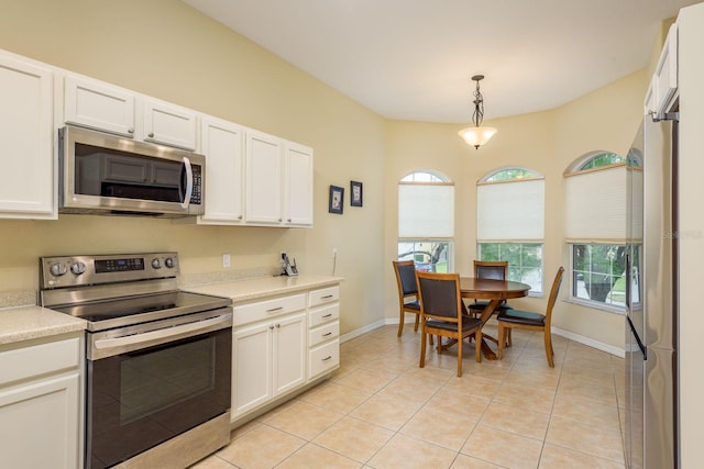kitchen with white cabinets, appliances with stainless steel finishes, light countertops, hanging light fixtures, and baseboards