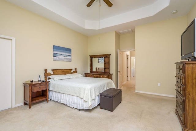 bedroom featuring ceiling fan, light colored carpet, visible vents, a raised ceiling, and baseboards