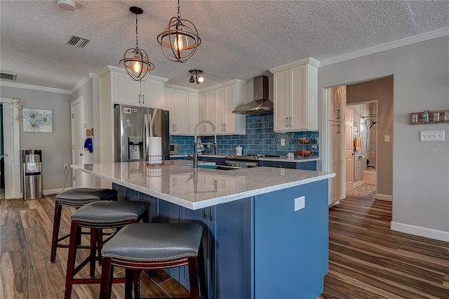 kitchen with wall chimney range hood, stainless steel fridge with ice dispenser, visible vents, and dark wood-style floors