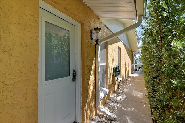 entrance to property featuring stucco siding and fence