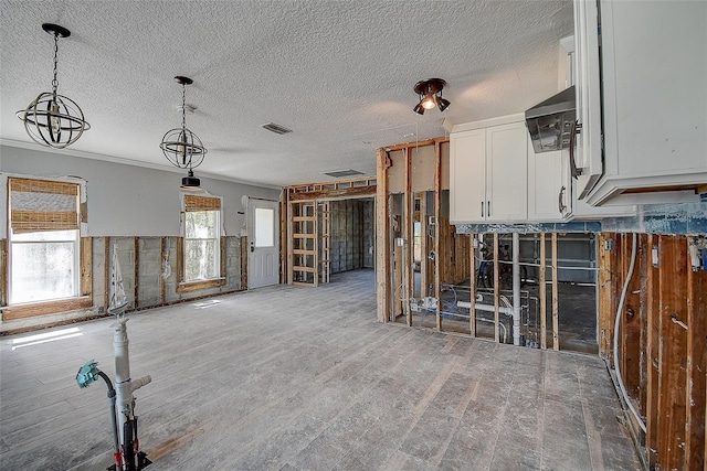 unfurnished living room with visible vents, wood finished floors, ornamental molding, and a textured ceiling