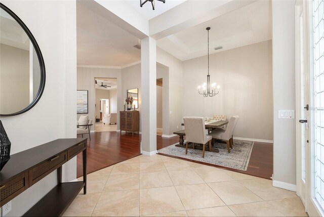 dining space with ornamental molding, ceiling fan with notable chandelier, baseboards, light tile patterned flooring, and visible vents