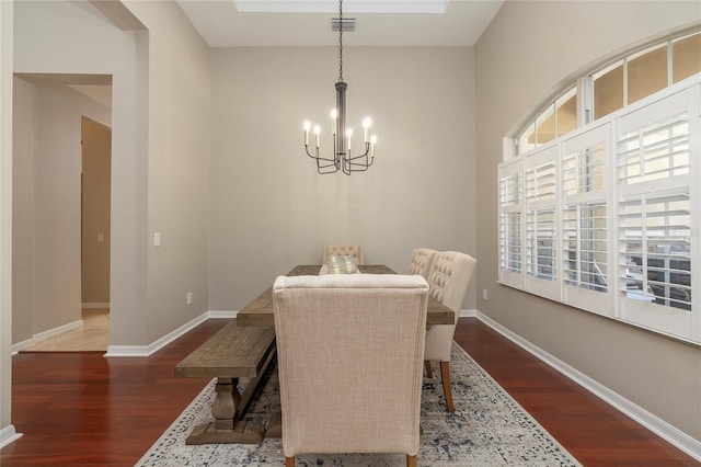dining area with baseboards, visible vents, wood finished floors, and a notable chandelier