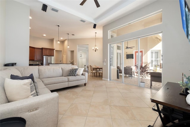 living room with ceiling fan with notable chandelier, visible vents, a towering ceiling, and light tile patterned floors