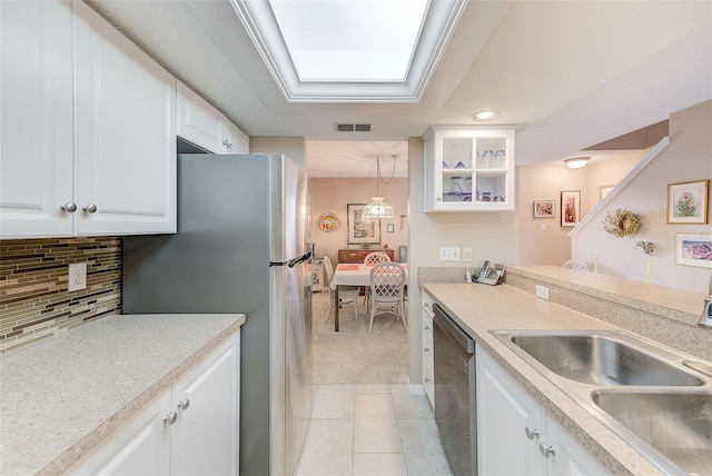 615 Garland Cir, Indian Rocks Beach, FL 33785 - kitchen featuring stainless steel dishwasher, light carpet, a sink, white cabinets, and light tile patterned floors