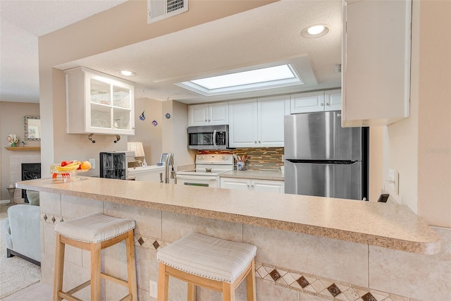 615 Garland Cir, Indian Rocks Beach, FL 33785 - kitchen with appliances with stainless steel finishes, a peninsula, white cabinets, a kitchen bar, and recessed lighting