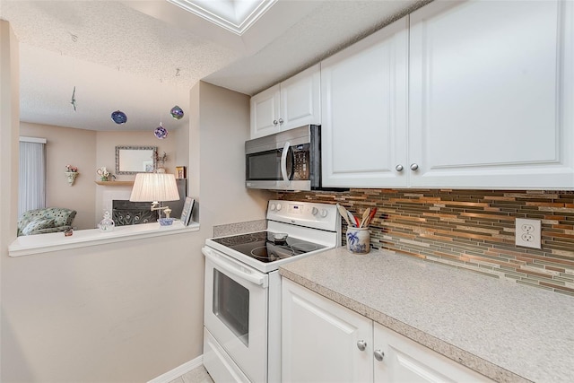 615 Garland Cir, Indian Rocks Beach, FL 33785 - kitchen with white electric range, stainless steel microwave, tasteful backsplash, white cabinetry, and light countertops