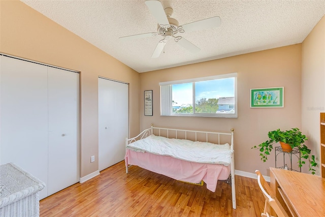 615 Garland Cir, Indian Rocks Beach, FL 33785 - bedroom featuring light wood-style floors, a textured ceiling, ceiling fan, multiple closets, and baseboards