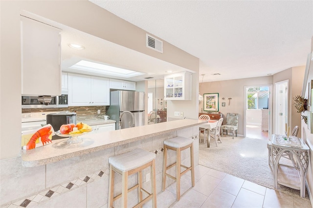 615 Garland Cir, Indian Rocks Beach, FL 33785 - kitchen with appliances with stainless steel finishes, light countertops, light carpet, a peninsula, and light tile patterned floors