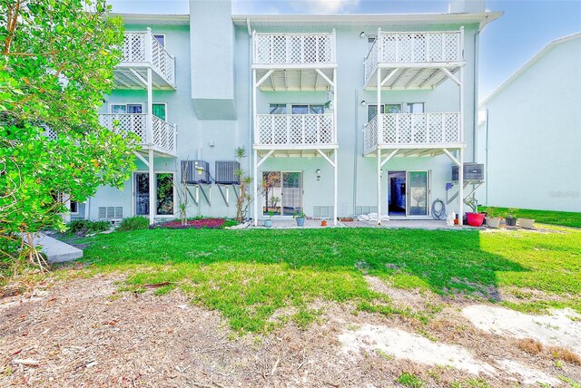 615 Garland Cir, Indian Rocks Beach, FL 33785 - rear view of house featuring stucco siding, a lawn, and central AC