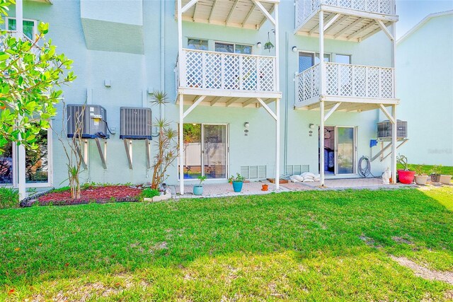 615 Garland Cir, Indian Rocks Beach, FL 33785 - rear view of house with stucco siding, a lawn, and central AC unit