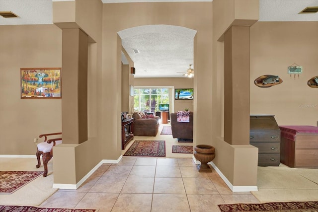 corridor with baseboards, a textured ceiling, visible vents, and tile patterned flooring