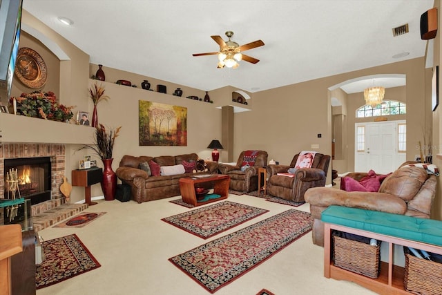 carpeted living area with a ceiling fan, arched walkways, a fireplace, and visible vents