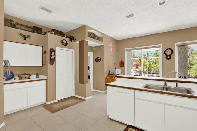 kitchen featuring white cabinetry, a sink, visible vents, and white appliances
