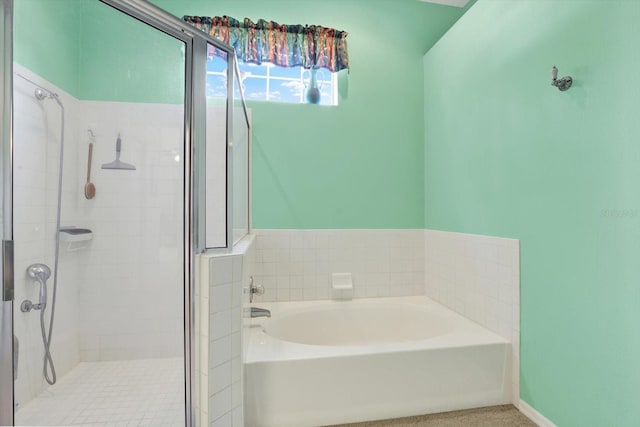 bathroom with a bath, baseboards, and a stall shower