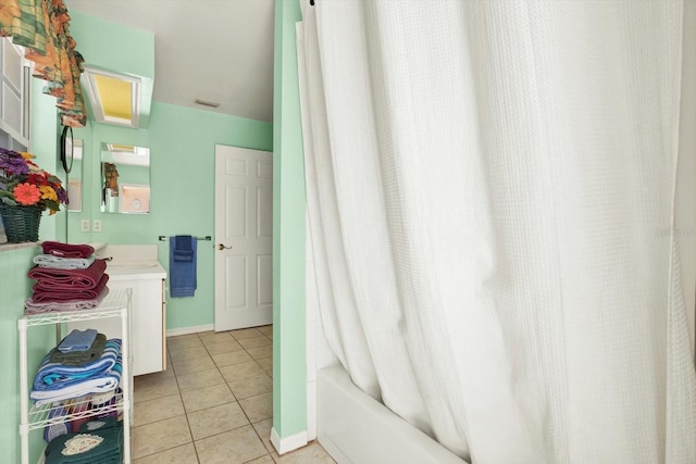 full bathroom with tile patterned floors, vanity, shower / bath combo with shower curtain, baseboards, and visible vents