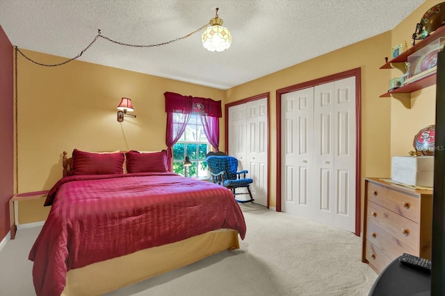 carpeted bedroom featuring multiple closets and a textured ceiling