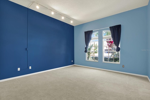 spare room with baseboards, a textured ceiling, track lighting, and carpet
