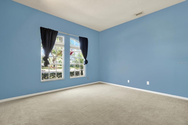 carpeted spare room featuring baseboards, visible vents, and a textured ceiling