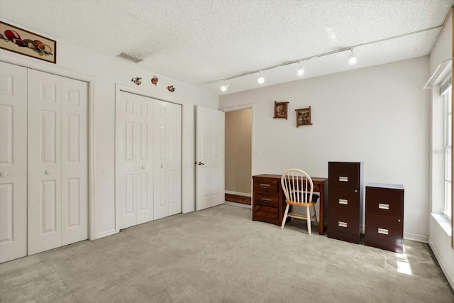 office area with carpet flooring, visible vents, a textured ceiling, and a wealth of natural light