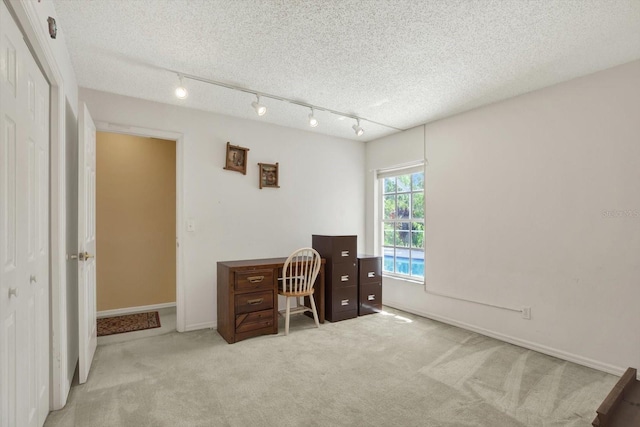 carpeted office space with baseboards, track lighting, and a textured ceiling