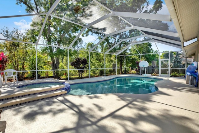 view of swimming pool with glass enclosure, a pool with connected hot tub, and a patio