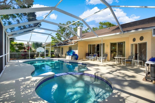 view of swimming pool with a patio, a pool with connected hot tub, and glass enclosure