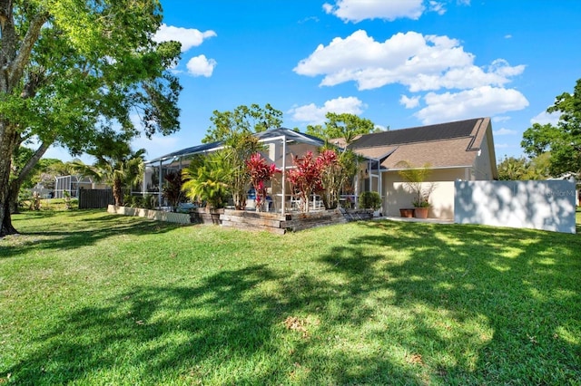 rear view of property with glass enclosure, stucco siding, fence, and a yard