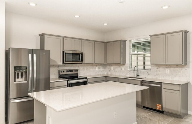 kitchen featuring stainless steel appliances, gray cabinetry, a sink, and tasteful backsplash