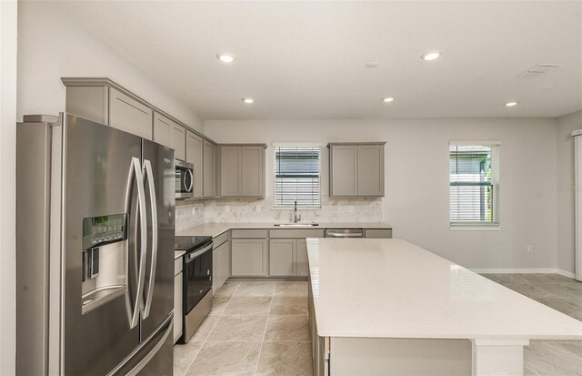 kitchen with plenty of natural light, a sink, gray cabinets, and appliances with stainless steel finishes