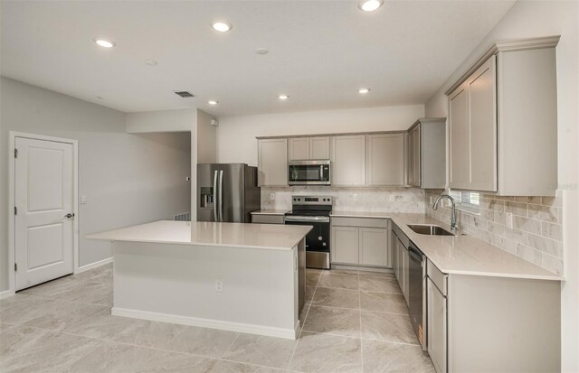 kitchen featuring a sink, appliances with stainless steel finishes, a kitchen island, and gray cabinetry