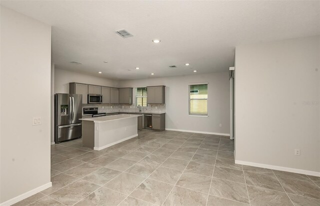 kitchen with visible vents, light countertops, gray cabinets, tasteful backsplash, and appliances with stainless steel finishes