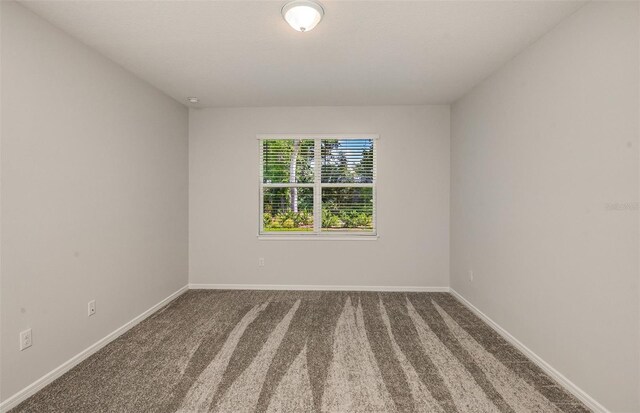 carpeted spare room featuring baseboards