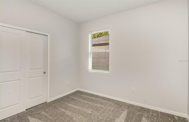 unfurnished bedroom featuring carpet floors, baseboards, and a closet