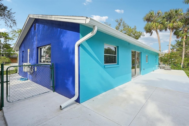 1832 Flamingo Dr, North Fort Myers, FL 33917 - view of side of home featuring a gate, stucco siding, fence, and a patio