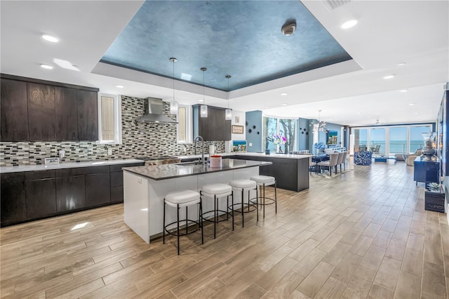 19816 Gulf Blvd Unit 201, Indian Shores, FL 33785 - kitchen with a sink, a kitchen breakfast bar, wall chimney exhaust hood, a raised ceiling, and a center island with sink