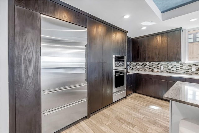 19816 Gulf Blvd Unit 201, Indian Shores, FL 33785 - kitchen featuring light wood-style flooring, light stone counters, dark brown cabinetry, backsplash, and a warming drawer