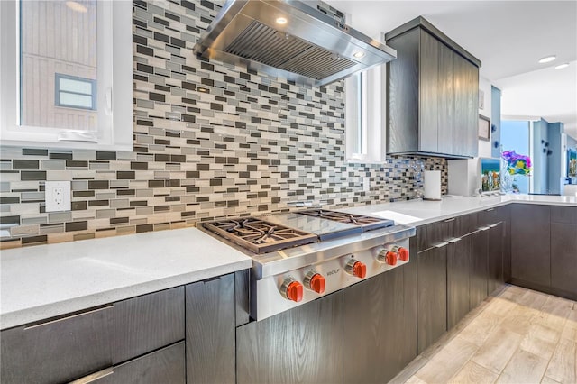 19816 Gulf Blvd Unit 201, Indian Shores, FL 33785 - kitchen with stainless steel gas stovetop, backsplash, light countertops, and wall chimney exhaust hood