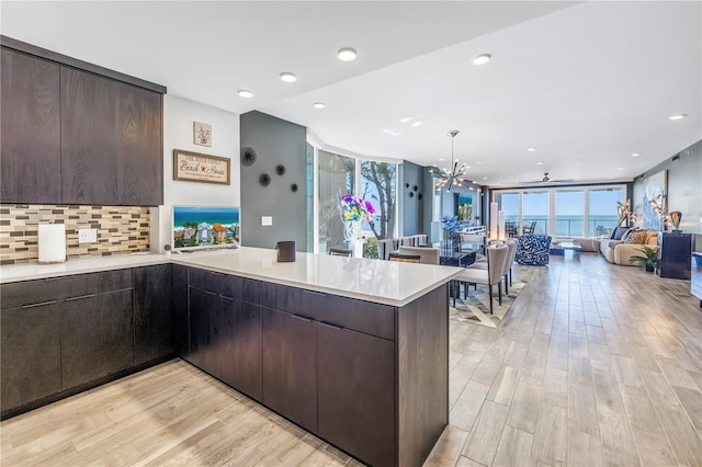 19816 Gulf Blvd Unit 201, Indian Shores, FL 33785 - kitchen with light wood-style flooring, dark brown cabinets, open floor plan, a peninsula, and light countertops