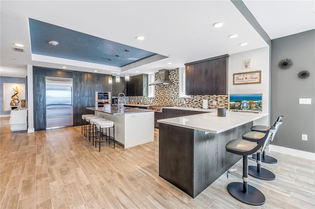19816 Gulf Blvd Unit 201, Indian Shores, FL 33785 - kitchen with a breakfast bar, a raised ceiling, wall chimney range hood, and appliances with stainless steel finishes