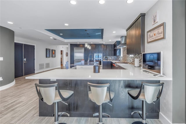 19816 Gulf Blvd Unit 201, Indian Shores, FL 33785 - kitchen with light countertops, wall chimney exhaust hood, decorative backsplash, and recessed lighting