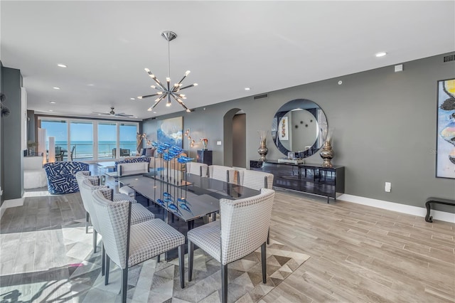 19816 Gulf Blvd Unit 201, Indian Shores, FL 33785 - dining area with ceiling fan with notable chandelier, recessed lighting, arched walkways, baseboards, and light wood-style floors