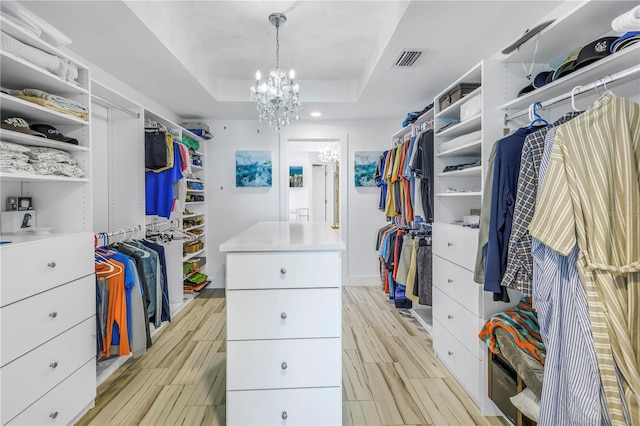 19816 Gulf Blvd Unit 201, Indian Shores, FL 33785 - walk in closet featuring a tray ceiling, an inviting chandelier, wood finish floors, and visible vents