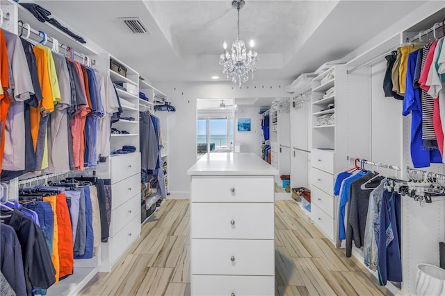 19816 Gulf Blvd Unit 201, Indian Shores, FL 33785 - walk in closet featuring wood finish floors, a notable chandelier, visible vents, and a raised ceiling