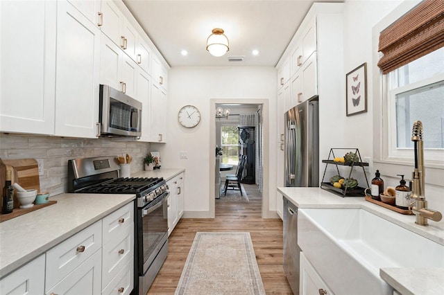 2910 W Aquilla St, Tampa, FL 33629 - kitchen with stainless steel appliances, a sink, light wood-style flooring, tasteful backsplash, and white cabinets